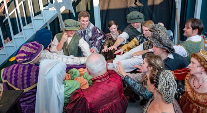 the cast of Romeo and Juliet join hands backstage at the Cascades Park amphitheater